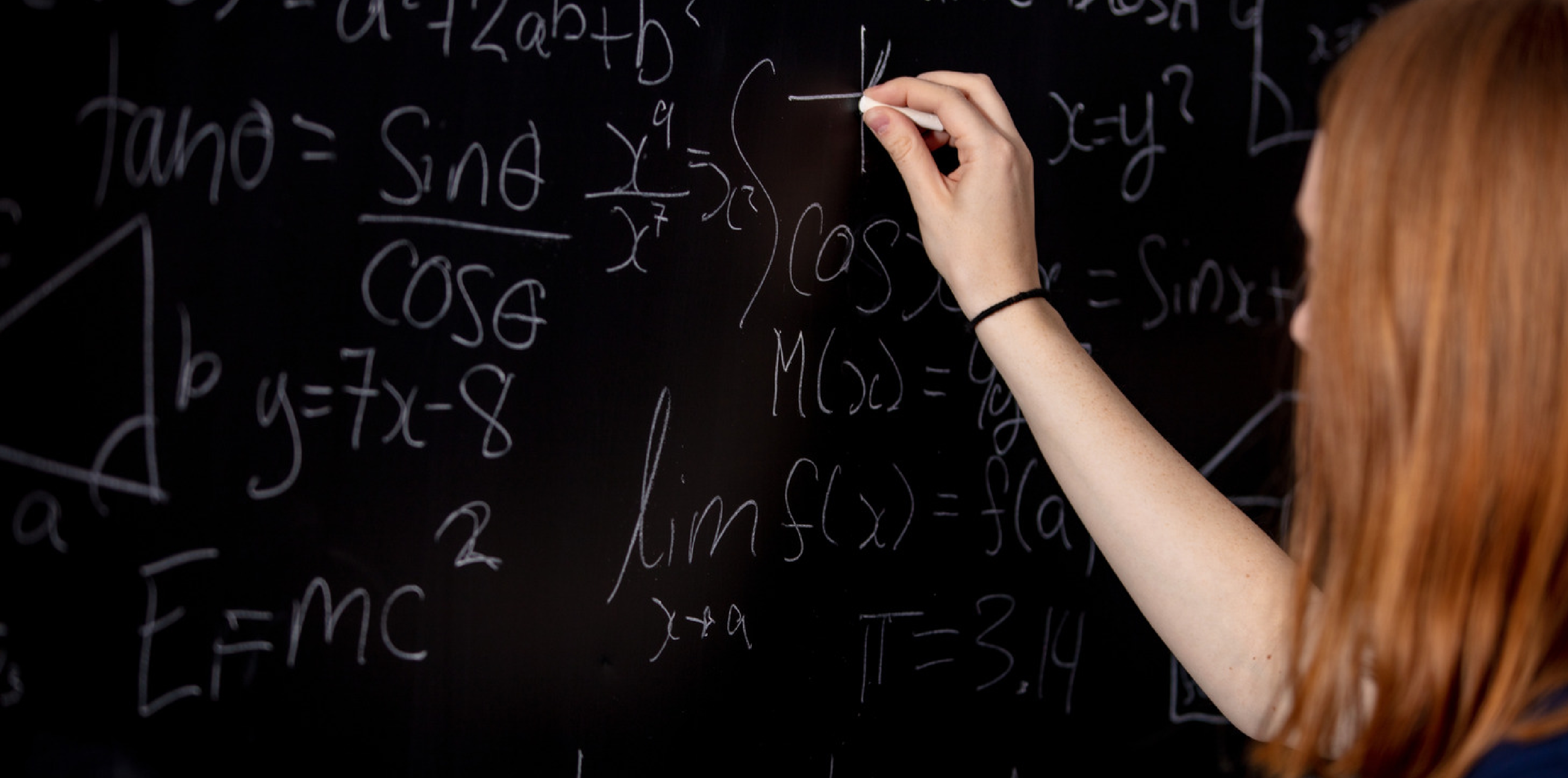 Actuarial science student writing formulae on a blackboard